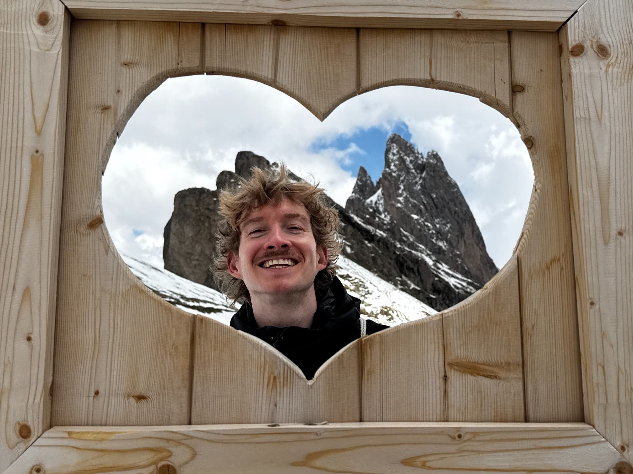 Mathew Croft in the Dolomites framed by a wooden heart